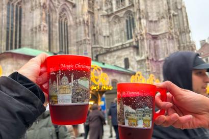 Two holiday mugs clinking with the St. Stephens Cathedral in the background. 