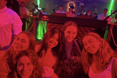 My friends and I smiling at Mae West, illuminated by red lights