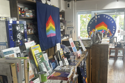 Shelves of LGBTQ books and resources with flags in the background