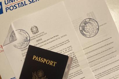 An image of a closed passport with a visa letter and envelope behind it.