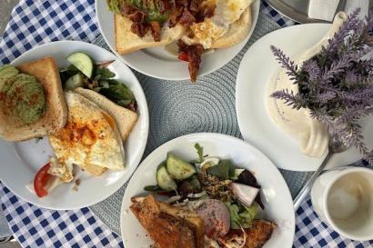 Photo from above of three plates filled with breakfast food, coffee cups, and plant on a small table