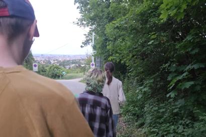 Three friends hike down Kahlenberg as the sun sets over the city.