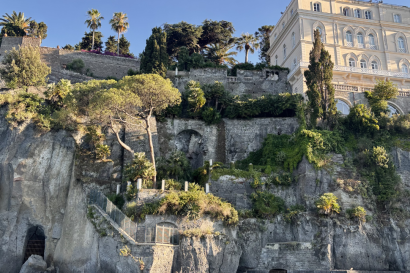 A lush cliff leading into blue water