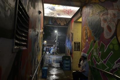 Picture of a dark alley with a chef on their smoke break.