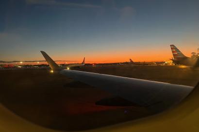View from an airplane in Boston at Logan Airport, with the sunset and terminal visible outside.