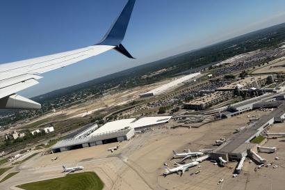 A view from the window of an airplane showing an aerial view of the Cleveland Hopkins airport on a sunny day with crystal clear skies.