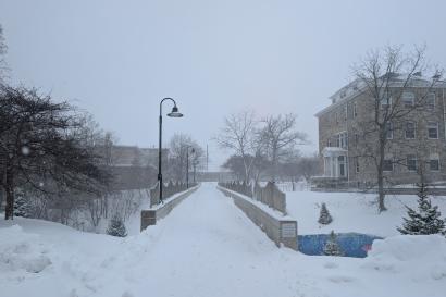 A bridge at Lawrence University in Appleton in dim light, covered in snow.