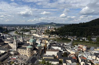 An aerial view of Salzburg, taken from the fortress. There are many houses and buildings below, including a cathedral.