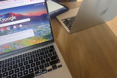 Two computers on a table sitting on a wooden table.