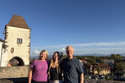 3 people stand on a hill with a castle in the background