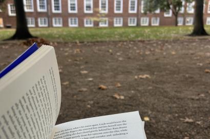 Open book in public garden with brick building and trees in background