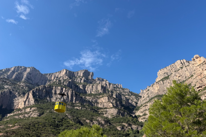 Yellow tram on a zipline in front of mountains