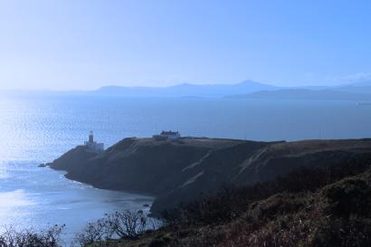 Cliffside lighthouse overlooking the sea under a clear blue sky. This alt text was added with Al; accuracy may vary.