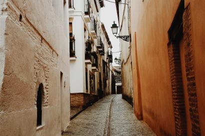 Three people smiling near ancient ruins.

Cliffs and ocean under cloudy skies.

Metal sculpture beside a brick building.

Person on a balcony with a city view at night.

Narrow cobblestone alley between buildings. This alt text was added with Al; accuracy may vary.