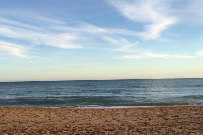 Narrow European street lined with white buildings under a blue sky. This alt text was added with Al; accuracy may vary.