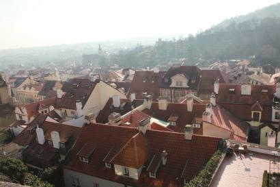Rooftops of a European town with red tiles, misty hills in the background. This alt text was added with Al; accuracy may vary.