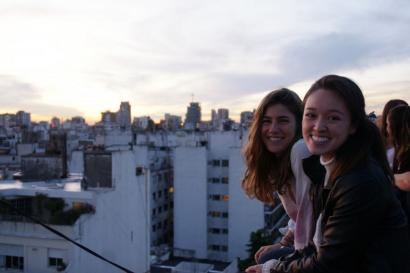 Two people smiling on a rooftop at sunset, overlooking Buenos Aires skyline. This alt text was added with Al; accuracy may vary.