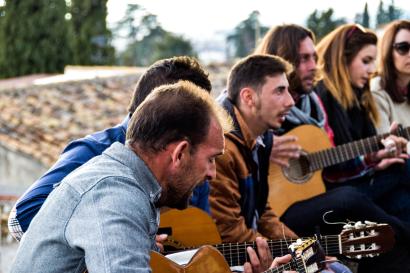 Musicians playing acoustic guitars outdoors, focused and engaged. This alt text was added with Al; accuracy may vary.