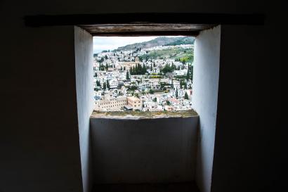View through a window, overlooking a city with greenery and hills in the distance. This alt text was added with Al; accuracy may vary.