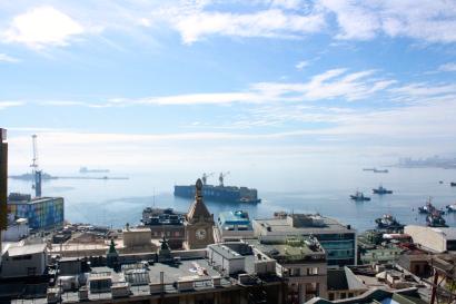 Harbor view with ships, city rooftops, and a partly cloudy sky. This alt text was added with Al; accuracy may vary.