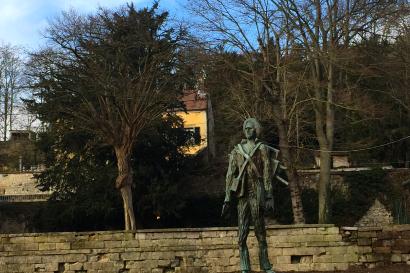 Squirrel hanging upside down on a branch with red berries in winter. This alt text was added with Al; accuracy may vary.