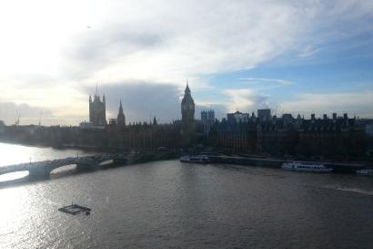 River view of the London skyline with Big Ben and the Houses of Parliament under a cloudy sky.