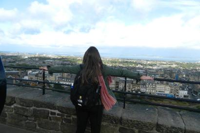 Person overlooking city view in Edinburgh from a stone terrace. This alt text was added with Al; accuracy may vary.
