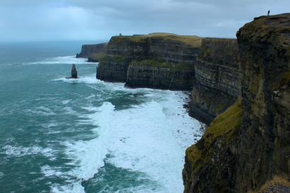 Ancient stone archway with three people smiling in foreground. This alt text was added with Al; accuracy may vary.
