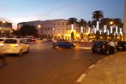 Clay pots and tagines displayed outdoors under palm trees at a market.

Dimly lit shop filled with hanging lamps and decorative items.

Five friends smiling by the waterfront on a sunny day.

Metal container with cooked food next to a small bowl on a table.

Cars drive around a city square with lit buildings and palm trees at dusk. This alt text was added with Al; accuracy may vary.