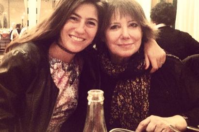 A small child moving in front of a group of smiling people crouched on a street at sunset. This alt text was added with Al; accuracy may vary.