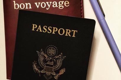 Crème brûlée in a white ramekin with caramelized top.

People posing with a large cat mascot in a public area.

Three people with guitars smiling under a bridge, one seated, with traffic cones nearby.

US passport and "bon voyage" notebook with a pen on a surface. This alt text was added with Al; accuracy may vary.