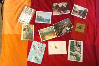 Postcards scattered on a colorful bedspread, featuring landscapes and art. This alt text was added with Al; accuracy may vary.