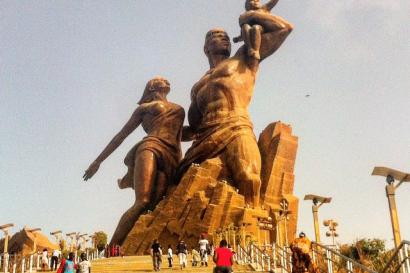 Bronze statue of a family on a large stone base with people walking up steps. This alt text was added with Al; accuracy may vary.