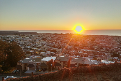Sunset over a cityscape with a glowing horizon and scattered buildings. This alt text was added with Al; accuracy may vary.