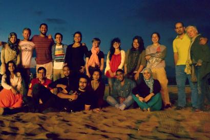 Group of people posing on a beach at dusk. This alt text was added with Al; accuracy may vary.