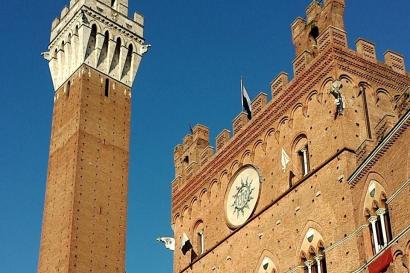 Two people in hats smiling, with a historic cathedral in the background.

Brick tower and building against a clear blue sky. This alt text was added with Al; accuracy may vary.