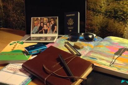 Travel essentials on a table: journal, map, passport, and family photo. This alt text was added with Al; accuracy may vary.