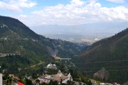 Mountain valley view with hills, clouds, and distant landscape. This alt text was added with Al; accuracy may vary.