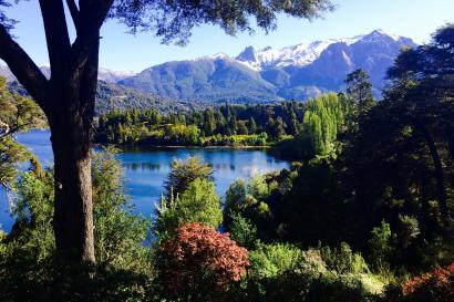 Group exploring grassy field by autumn mountains.  
Serene lake and mountain view with lush greenery. This alt text was added with Al; accuracy may vary.