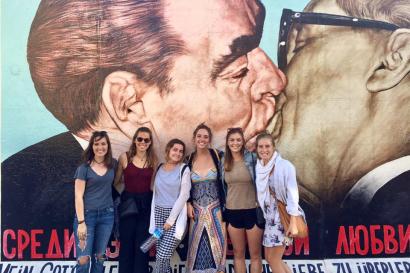 A group of students standing in front of the Berlin Wall.