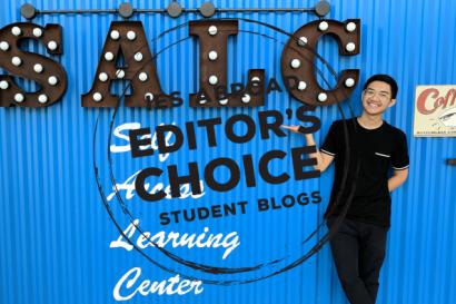 student in front of SALC sign on blue wall with editor's choice logo