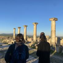 Students standing in front of ancient roman pillars in the ruins of Volubolis