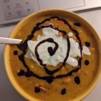 Bowl of orange, pumpkin soup with cream and balsamic vinegar swirled on top.