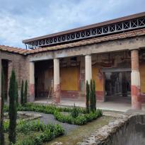 Shown is the garden of a ruined courtyard in Pompeii, boasting an impressive fresco