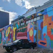 A colorful, abstract mural with a truck parked in front of it