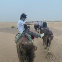 A man sitting side saddle on a camel