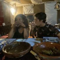 Two people drinking water in front of dinner in a tent