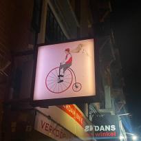 A sign of a man on an old fashioned bicycle with one large wheel 