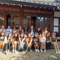 Image of students sitting in front of a traditional Korean house, a hanok 