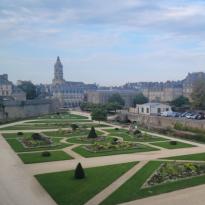 Overview of a garden within the defense walls in Vannes, France with city structures in the background.